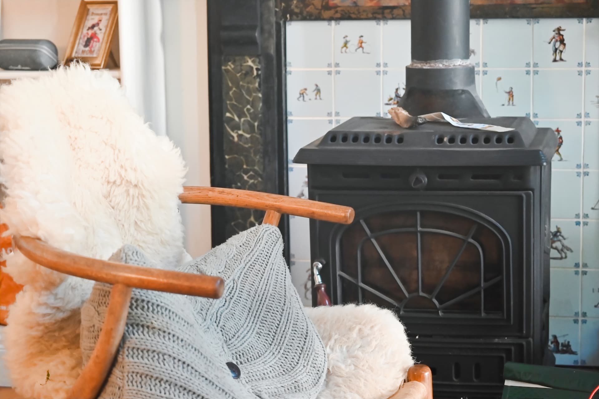 A wooden chair with sheepskin and a knitted throw beside the clinic's wood stove