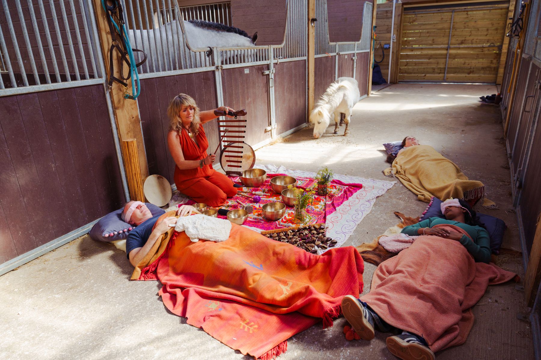 Two people resting under blankets during a sound bath in the stable barn