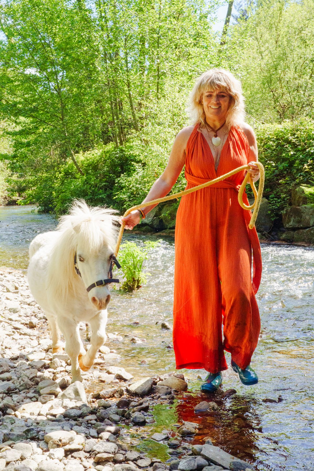 Carolyn leading a pony along the river's edge