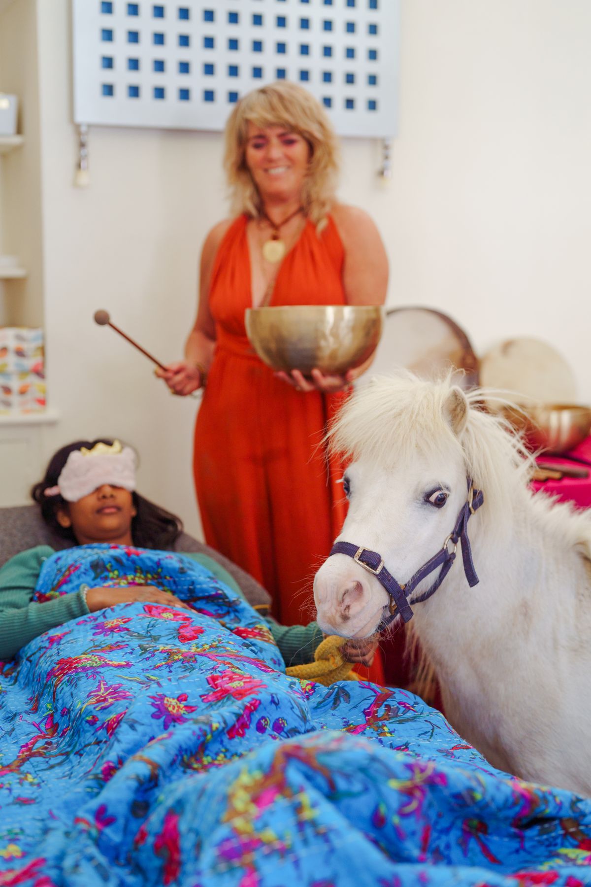 Carolyn sounding a bowl beside a resting client and pony