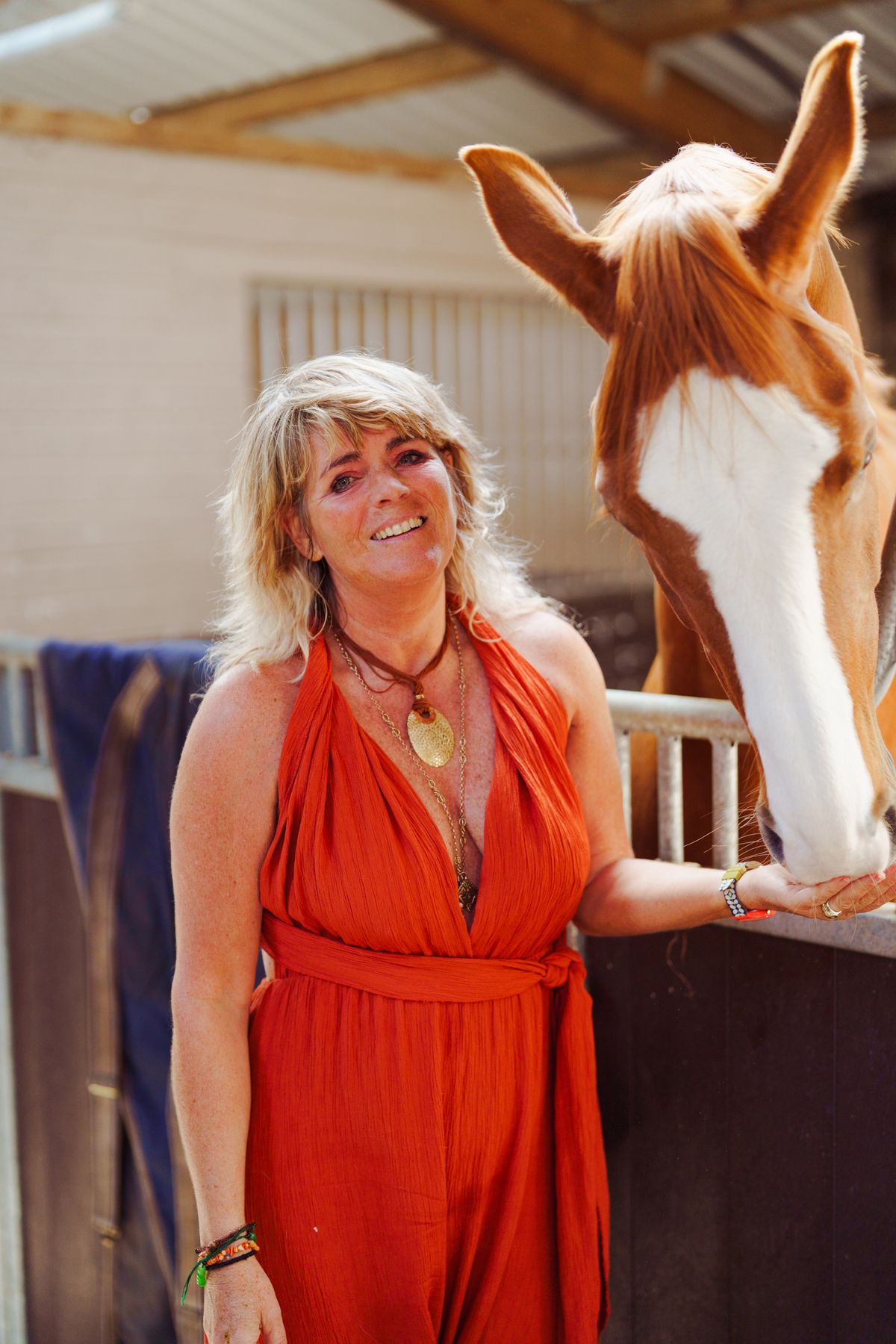 Carolyn resting a hand on a chestnut horse's neck