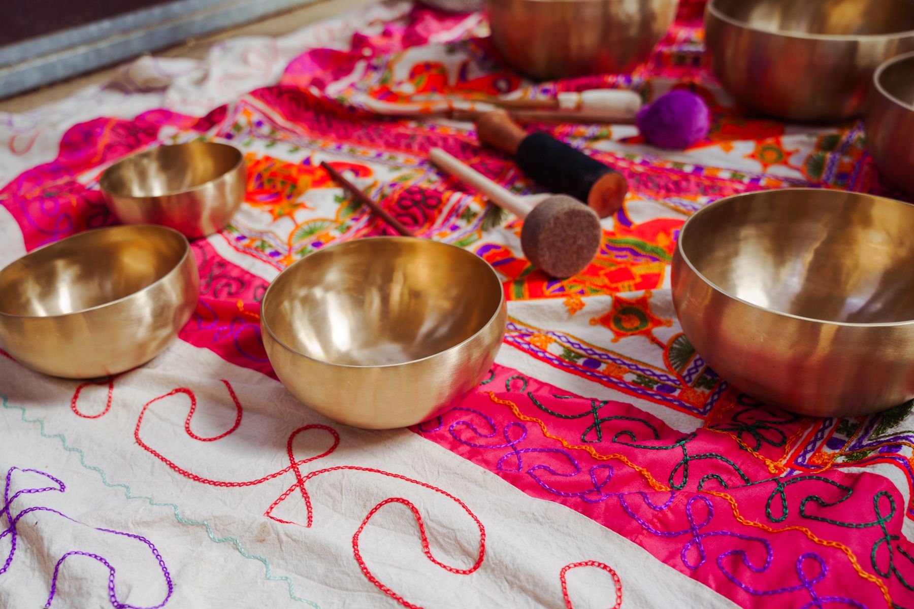 Brass singing bowls arranged on a bright embroidered cloth